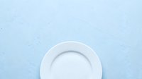 Empty white plate on light blue textured surface, overhead view for food styling, restaurant menu design, culinary photography, and dining concepts.