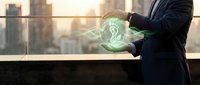 Businessman holding glowing digital brain hologram with neural networks on city rooftop at sunset representing artificial intelligence and innovation.