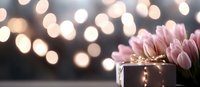 Pink tulip bouquet and wrapped gift box against blurred bokeh lights background creating romantic festive atmosphere for special occasion celebration.
