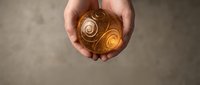 Caucasian male hands holding glowing golden sphere with spiral energy patterns, representing power, innovation, and technology concepts for business and creative projects.