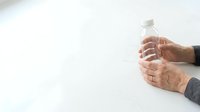 Man holding clear water bottle with both hands against white background, suitable for health, wellness, hydration, fitness, and lifestyle marketing materials.