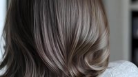 Soft waves of ash brown and silver balayage hair styled in modern loose curls, showing detailed texture and natural movement from behind. For beauty and hair salon promotion.