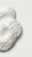 White foaming cleanser with bubbles on neutral background for skincare and beauty product advertising campaigns.