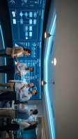 Diverse team of medical professionals analyzing patient data on advanced digital displays in modern healthcare facility control room.