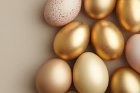 Golden and natural colored Easter eggs with metallic finish and delicate speckled pattern on neutral background, elegant holiday composition for spring celebrations.