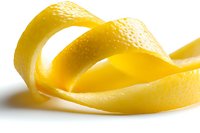 Fresh lemon peel spiral with textured yellow rind isolated on white background, macro shot showing citrus zest details for culinary and cocktail designs.