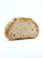 Sliced artisan bread loaf with golden crust and airy crumb structure, isolated on white background for bakery, food packaging, and culinary design projects.