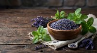 Dried lavender flowers in wooden bowl with fresh mint leaves on rustic table for aromatherapy, cooking, and natural wellness applications.