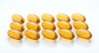 Golden omega-3 fish oil capsules arranged in neat rows on white background. Dietary supplements for heart health and wellness nutrition support.