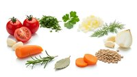 Fresh vegetables and herbs arranged in circle on white background including tomatoes carrots onions lentils and aromatic herbs for healthy cooking.
