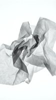 Crumpled white and gray tissue paper with flowing folds and shadows isolated on white background, suitable for design projects and creative compositions.