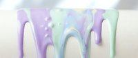 Pastel holographic paint drips flowing down white surface creating iridescent rainbow effect for modern artistic backgrounds and creative design projects.
