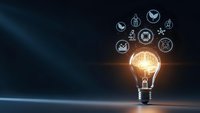 Glowing light bulb with business innovation icons on dark blue background representing creative ideas and entrepreneurship solutions.