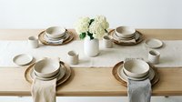 Elegant neutral ceramic dinnerware set arranged on wooden table with white hydrangea centerpiece for modern dining and home decor styling.