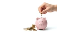 Hand dropping coin into pink piggy bank with golden coins scattered around on white background for savings and financial planning concepts.