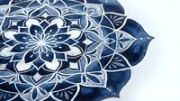 Intricate mandala pattern with geometric floral motifs in navy and white, featuring detailed symmetrical designs suitable for textile, wallpaper, and decorative applications.