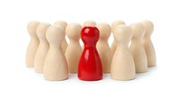 Red wooden pawn figure standing out among natural wood pawns on white background. Leadership, uniqueness, teamwork and business concept for presentations.