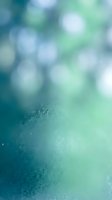 Frosted glass texture with soft teal and green bokeh light circles, creating a dreamy abstract background for design projects.