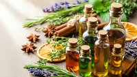 Essential oils in glass bottles with lavender, herbs and spices for aromatherapy, natural wellness and spa treatments on wooden background.