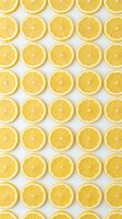 Bright yellow lemon slices arranged in a repeating grid pattern on white background, tiling seamlessly into a fresh citrus surface design.