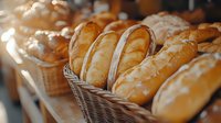 Fresh baked crusty bread loaves displayed in wicker baskets at bakery counter, golden brown French baguettes with crispy crust in warm lighting.