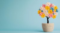 Decorative paper craft tree with colorful pastel flowers in woven basket pot against mint blue background. Creative spring home decor concept.