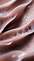 Smooth waves of melted milk chocolate with tiny bubbles and droplets creating artistic texture and pattern. Macro food photography for confectionery advertising.