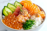 Fresh seafood poke bowl with salmon sashimi, tuna, shrimp, red caviar, cucumber slices and steamed rice garnished with green onions and sesame seeds.