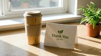Eco-friendly thank you card with soy ink beside a reusable bamboo travel mug on a wooden table in natural sunlight.