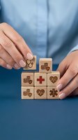 Healthcare professional arranging wooden blocks with medical icons including stethoscope, heartbeat, and emergency symbols, representing health insurance, wellness planning, and medical services concept.