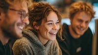 Young diverse professionals laughing together during casual business meeting or team building activity in modern office environment.