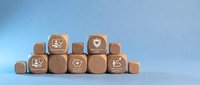 Wooden blocks with healthcare icons including telemedicine, preventive care, medical savings, and wellness journey arranged on a blue background.