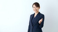 Professional Asian businesswoman in navy suit with crossed arms smiling confidently against white background for corporate presentations and marketing materials.
