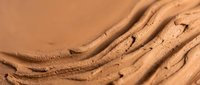 Smooth chocolate frosting swirls with rich creamy texture for baking and dessert backgrounds.