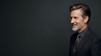 Middle-aged Caucasian male professional wearing dark blazer and gray shirt against neutral background, suitable for corporate, business, and executive portrait use.