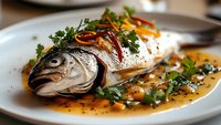 Whole roasted fish with herbs and vegetables on white plate, gourmet seafood dish for restaurant menu, culinary photography for food service industry.