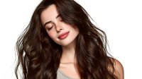 Young woman with flowing brunette hair and closed eyes smiling gently, showcasing healthy, voluminous locks for beauty and haircare advertising.