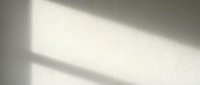 Soft window light casting diagonal shadows on neutral beige wall surface, creating minimalist abstract background for design and branding projects.