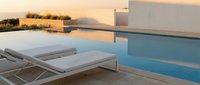 Luxury infinity pool with white lounge chairs at sunset, modern minimalist architecture, serene water reflection, premium resort vacation destination.