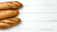 Fresh baguettes arranged on white wooden background with copy space. Traditional French bread composition for bakery menu or food design.