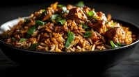 Aromatic spiced rice pilaf with tender meat pieces and fresh herbs served in black bowl on dark wooden surface for culinary presentations and recipe content.