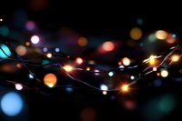 Glowing string lights creating magical bokeh effect against dark background, colorful defocused circles of blue, orange and pink lights create festive mood.