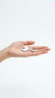 Open palm holding silver house key on white background for real estate and property concepts.