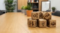 Wooden business concept blocks with corporate icons on office desk representing teamwork, innovation, strategy and leadership development.
