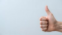 Hand showing thumbs up gesture against clean white background expressing approval, success and positive feedback for business presentations.