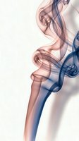 Elegant colorful smoke swirls in pink and blue tones creating flowing abstract patterns on light background for creative design projects.
