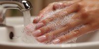 Hands washing with soap and water at bathroom sink for hygiene and cleanliness routine.