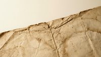 Cracked damaged wall with peeling paint and plaster showing deterioration and weathering effects on beige surface requiring repair and renovation work.