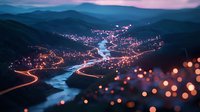 Aerial view of mountain valley with winding river and city lights creating magical evening atmosphere, long exposure captures light trails along roads at twilight.