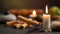 Relaxing spa scene with burning candles, smooth stones, bamboo sticks and dried lavender creating peaceful wellness atmosphere for meditation and aromatherapy.